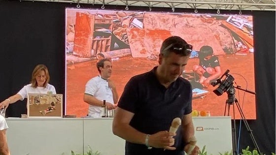 Angelines González y Fernando Sáenz, durante la presentación del helado que se dispone a degustar uno de los asistentes al festival gastronómico Mama; al fondo, imágenes del paisaje arrasado por la dana que inspiran su creacion.