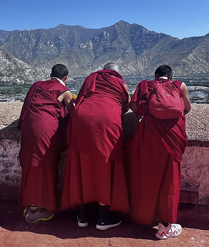Imagen secundaria 2 - El palacio Potala al atardecer. Un enorme cartel político con todos los mandatarios chinos de Mao a Xi Jinping en la explanada bajo el palacio, y tres monjes contemplando la Lhasa moderna desde un mirado del la fachada posterior del Potala.