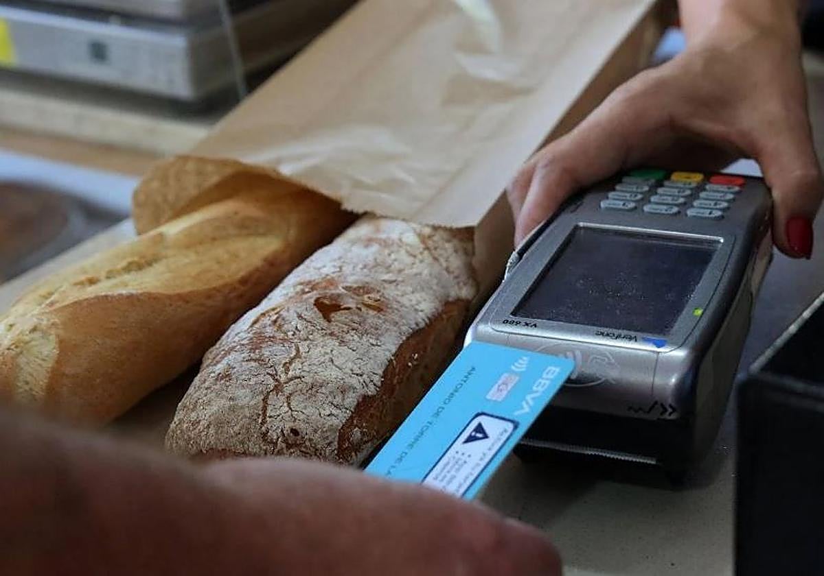 Un cliente paga una barra de pan con tarjeta.