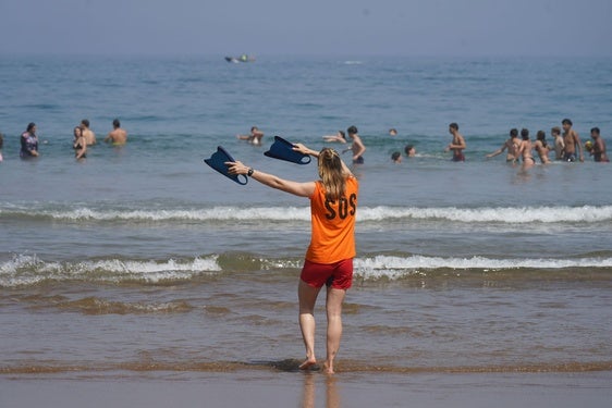 Una socorrista hace señales a un grupo de bañistas en la playa de Arriatera. .