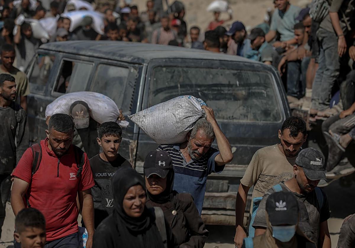 Gazatíes cargan con ayuda humanitaria.