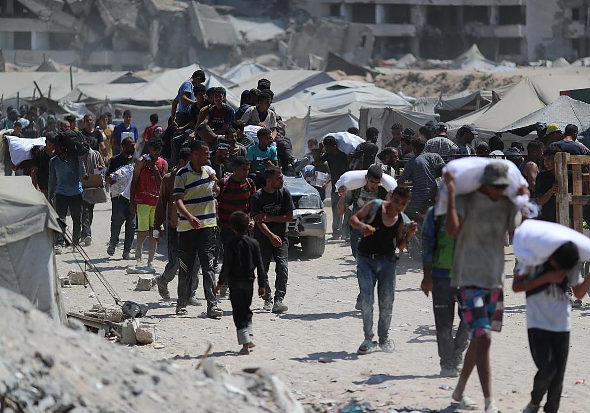 Un grupo de palestinos transporta ayuda humanitaria por una callle de Gaza.