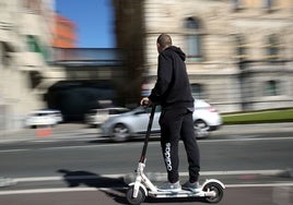 Un hombre se mueve por la ciudad en un patinete eléctrico.