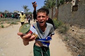 Jóvenes gazatíes con unas latas de comida en un centro de reparto.