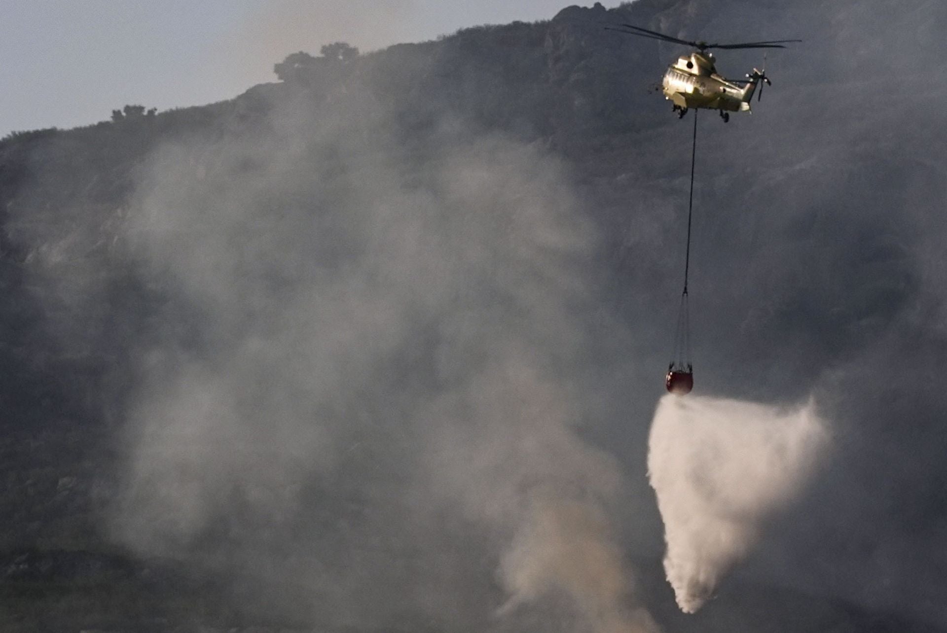 Un helicóptero trabaja en las labores de extinción del incendio que afecta a la Sierra de la Plata, en Tarifa (Cádiz).