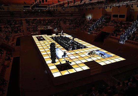 El escenario es una plataforma luminosa (de 30 metros de largo y 12 de ancho) con un foso en el centro que acoge la orquesta