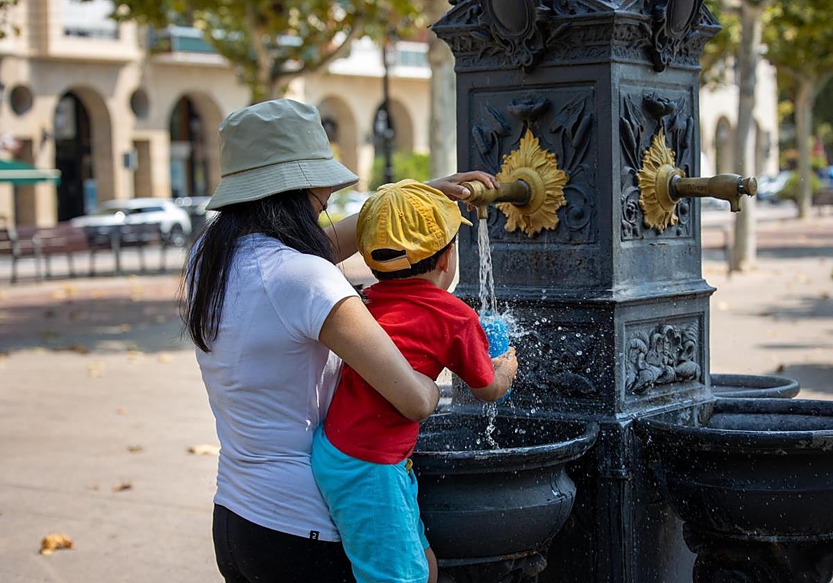 Una mujer y un niño llenan una botella para beber agua en Logroño