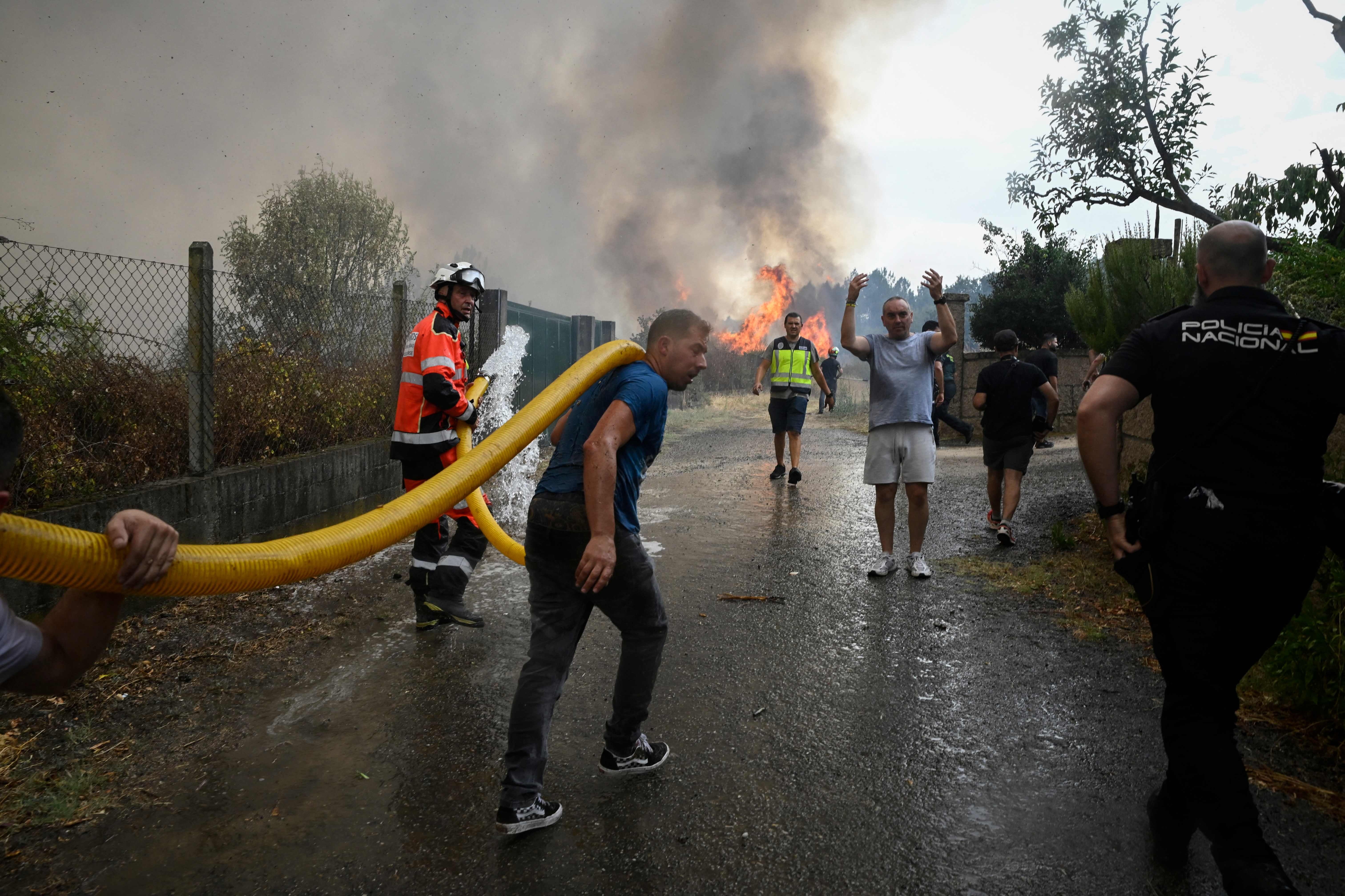 Vecinos, bomberos y agentes de la Policía Nacional cooperan para la extinción de los incendios en San Ciprián de Viñas, Orense.