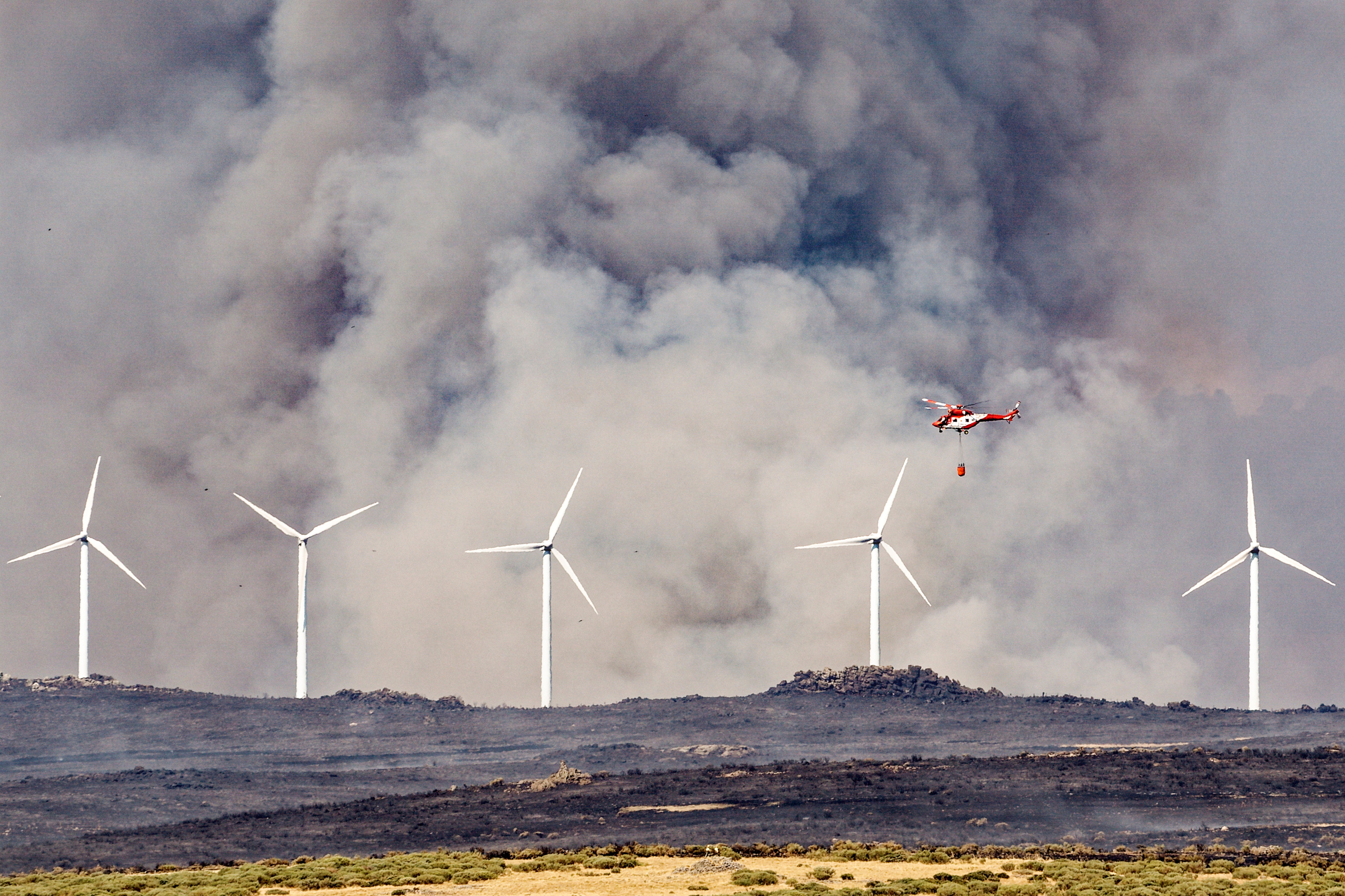 Un helicóptero trabaja  en labores de extinción del incendio en las proximidades de Urraca-Miguel, barrio anexionado de Ávila capital.