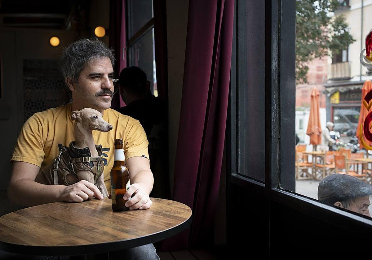 Ernesto Sevilla en un bar de Madrid junto a su galgo italiano, Elvis, que le acompaña desde 2019.
