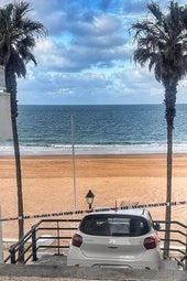 Un coche en unas escaleras de acceso a la playa en Rota (Málaga).