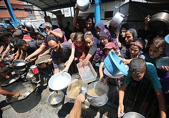 Palestinos aguardan para recoger algo de comida en Ciudad de Gaza.