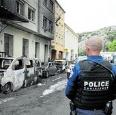 Violencia. Un agente hace guardia junto a cuatro vehículos policiales incendiados frente a la comisaría de Cavaillon durante una operación antidroga.