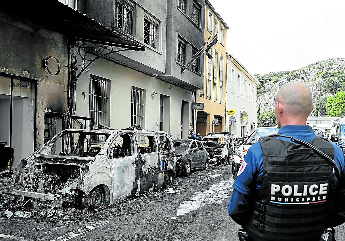 Violencia. Un agente hace guardia junto a cuatro vehículos policiales incendiados frente a la comisaría de Cavaillon durante una operación antidroga.