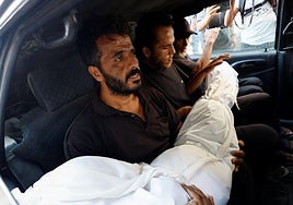 Varios hombres cargan el cuerpo de un gazatí muerto en un incendio provocado por Israel.