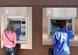 Dos personas sacan dinero de los cajeros de una entidad bancaria este miércoles en Madrid