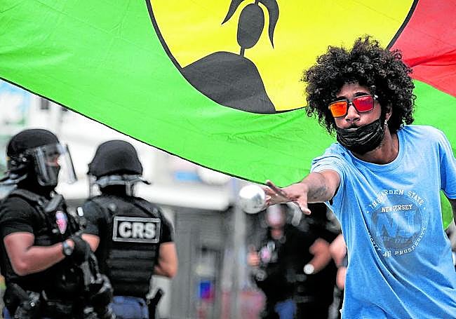 Un joven juega a la petanaca en Numea mientras patrullan las Compañías Republicanas de Sociedad