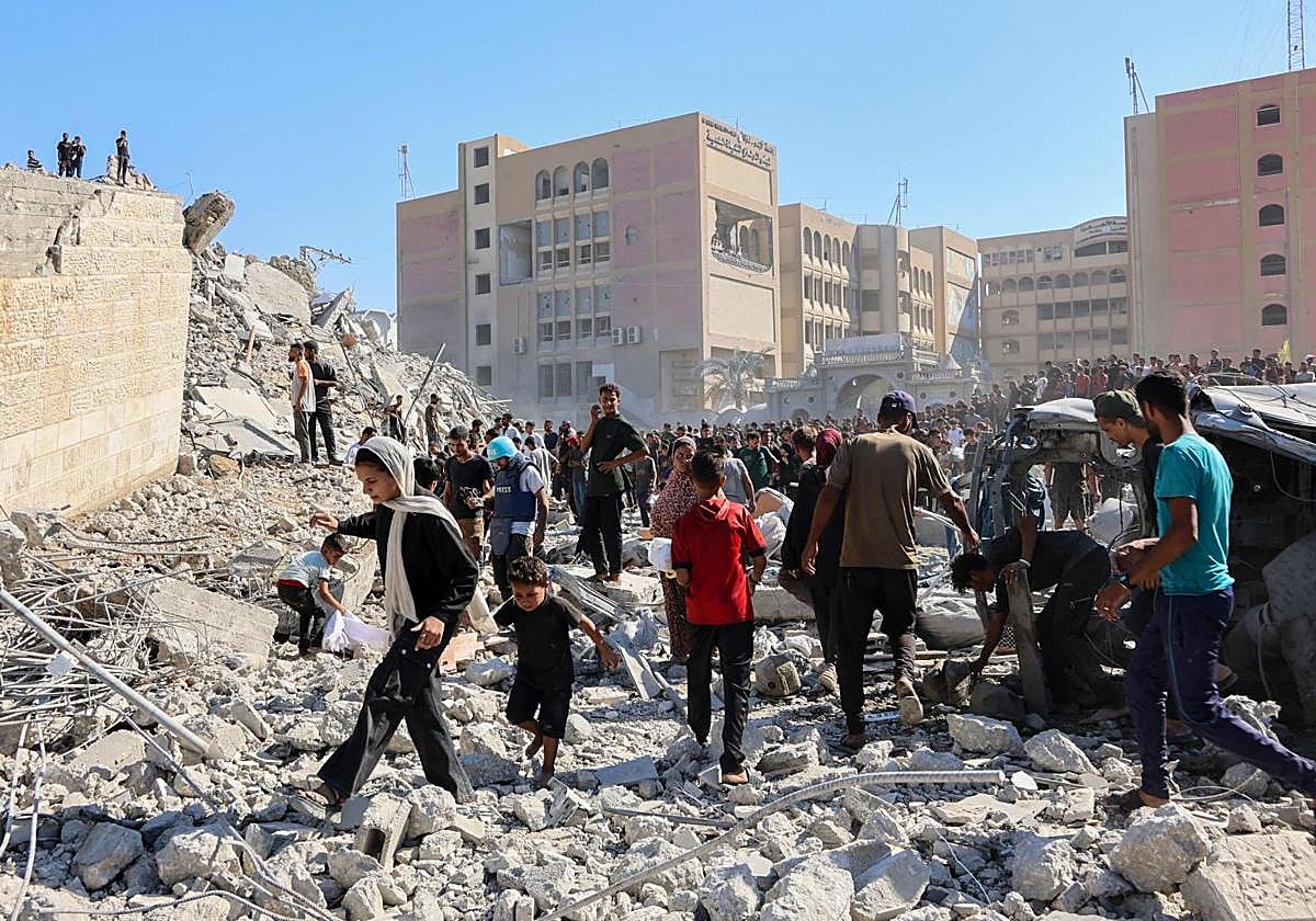 Decenas de palestinos caminan entre los escombros de un edificio de Ciudad de Gaza.