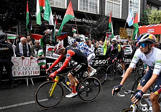 Los ciclistas pasan por delante de algunos manifestantes.