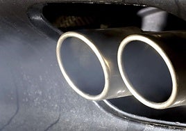 Humo procedente de la combustión de un motor de un coche sale de dos tubos de escape.