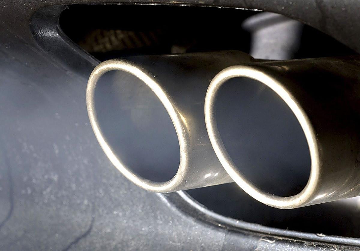 Humo procedente de la combustión de un motor de un coche sale de dos tubos de escape.