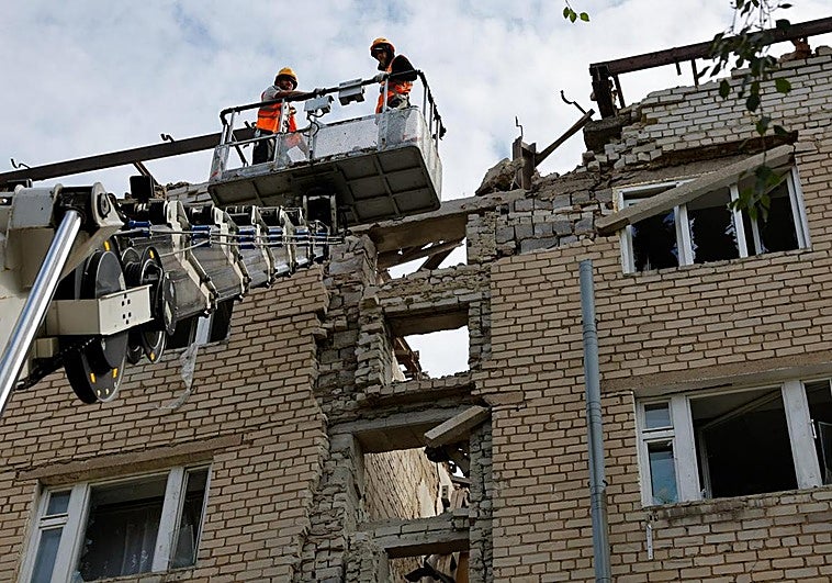Dos operarios ucranianos trabajan en un edificio bombardeado por Rusia en la región de Donetsk.