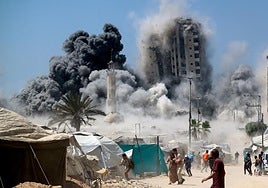 Un grupo de palestinos huye mientras se derrumba una torre de edificios en Ciudad de Gaza al ser alcanzada por un bombardeo israelí.
