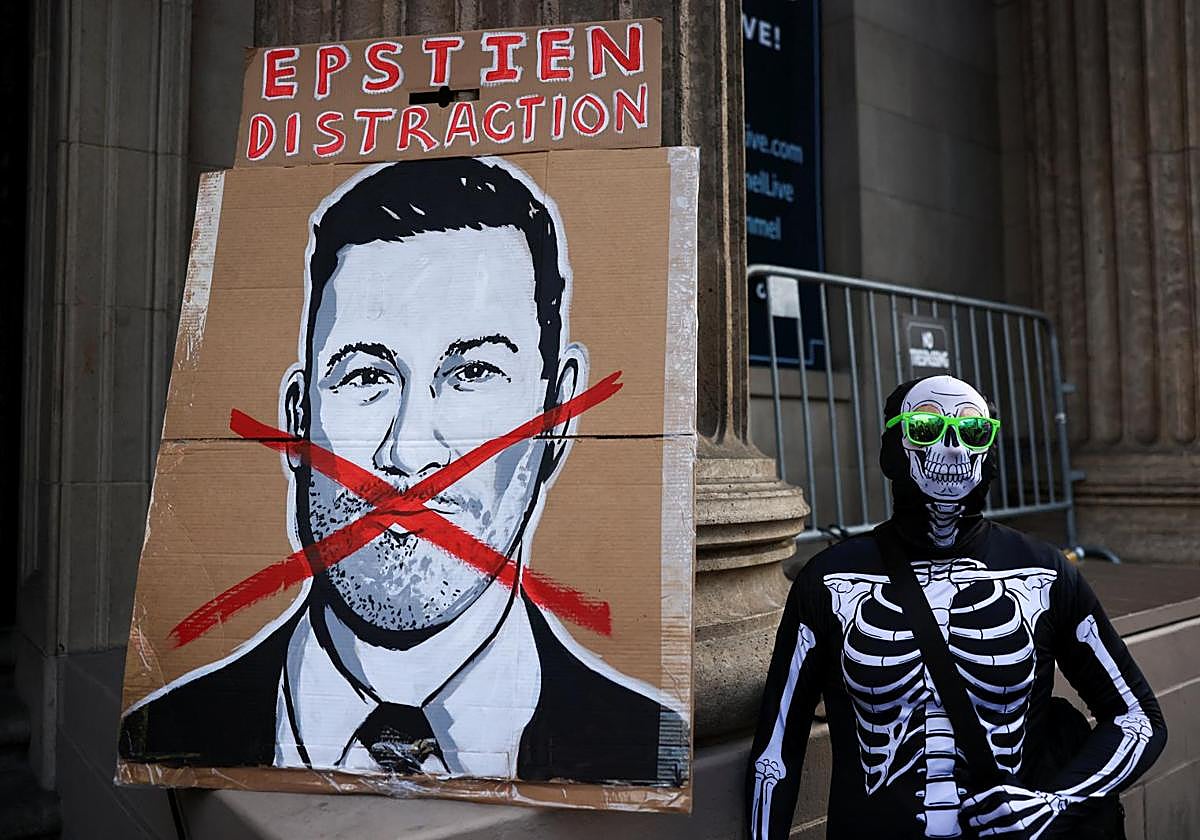 Un manifestante vestido con un traje de esqueleto junto a un cartel de Jimmy Kimmel durante una protesta por el despido del presentador.