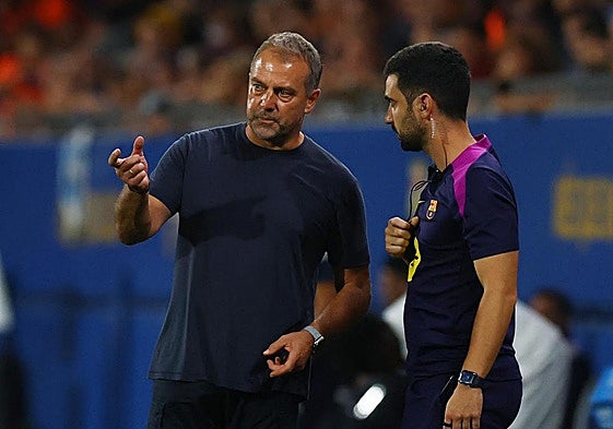 Hansi Flick habla con uno de sus ayudantes.