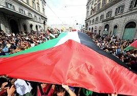 Cientos de manifestantes ondean una bandera palestia gigante por una calle de Roma.