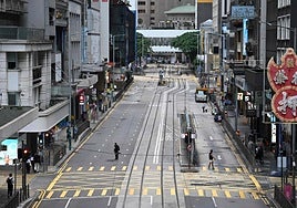 Peatones cruzan una calle vacía en el distrito central de Hong Kong, en alerta por la llegada del supertifón 'Ragasa'.