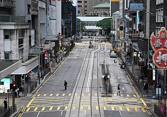 Peatones cruzan una calle vacía en el distrito central de Hong Kong, en alerta por la llegada del supertifón 'Ragasa'.