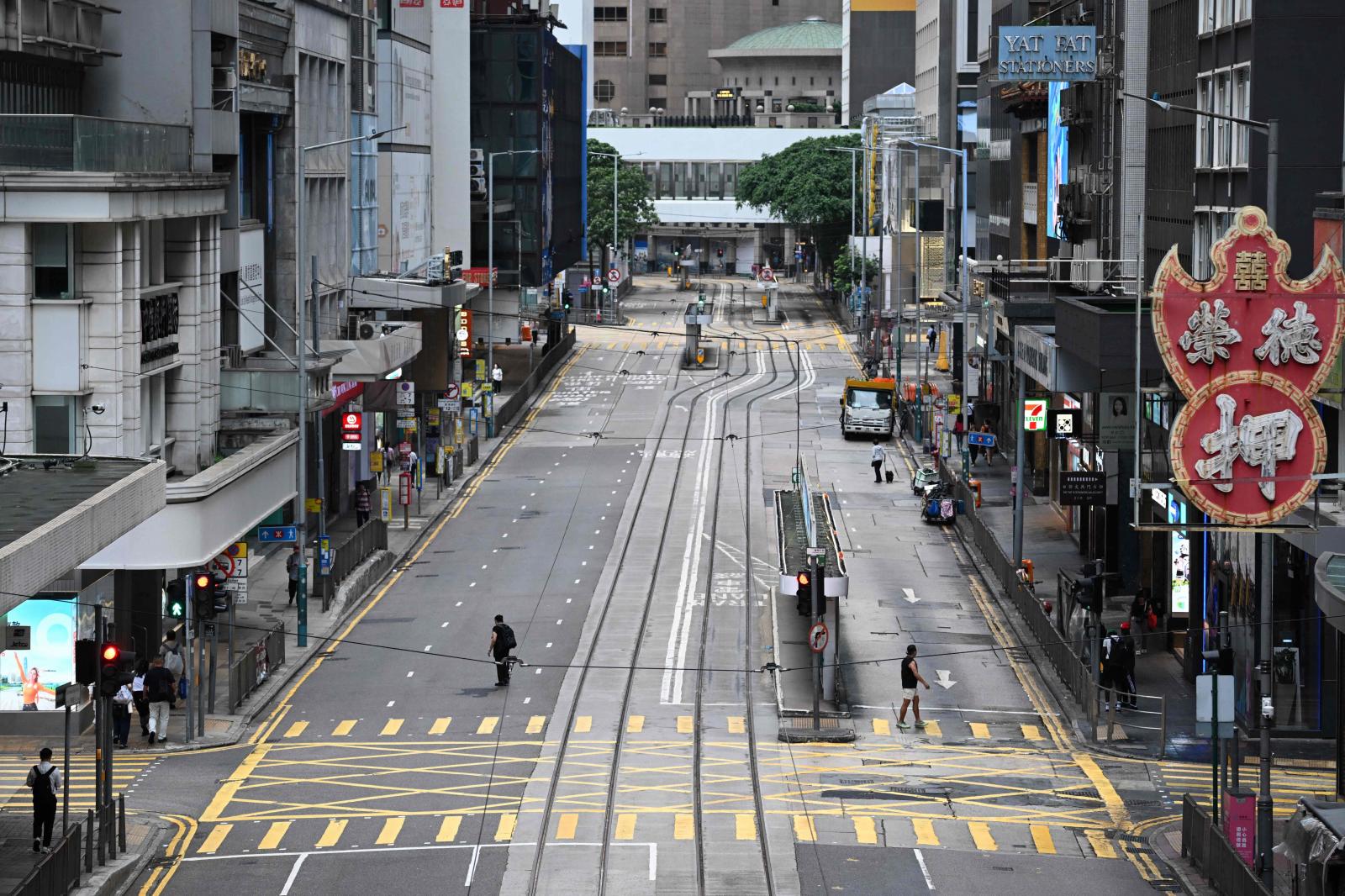 Peatones cruzan una calle vacía en el distrito central de Hong Kong, en alerta por la llegada del supertifón 'Ragasa'.