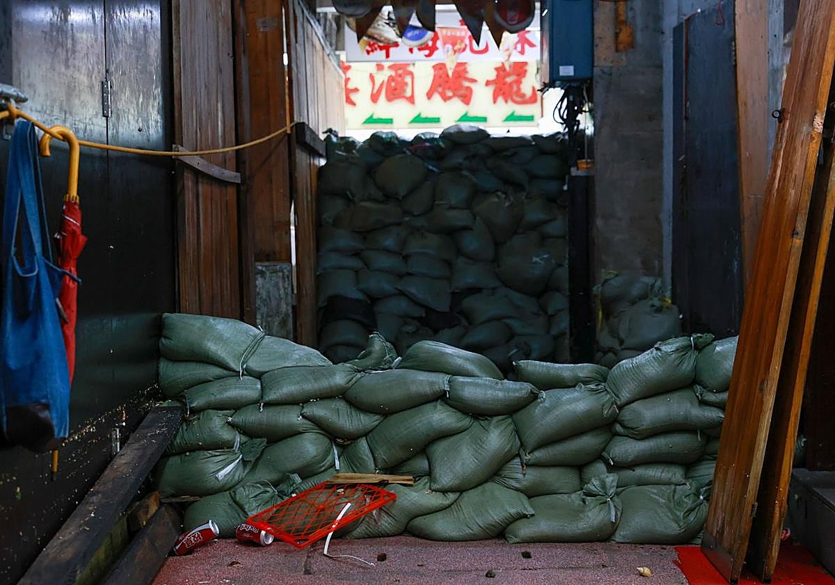 Imagen principal - Un hombre sostiene a su perro mientras camina por una calle de Macao; sacos de arena se apilan frente a un restaurante en Hong Kong y el lodo cubre una céntrica arteria de Hualien (Taiwán).