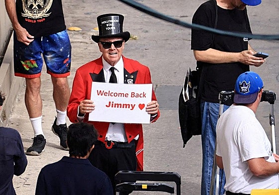 Gregg Donavan sostiene un cartel que dice «Bienvenido de nuevo, Jimmy» fuera del teatro donde se graba su programa.