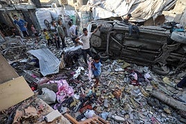 Una familia gazatí entre los restos de una casa destruida en un bombardeo israelí.