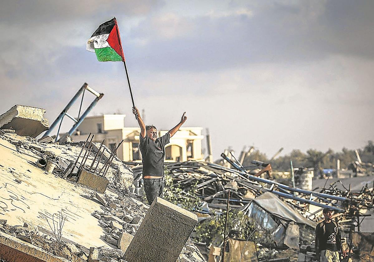 Un niño ondea una bandera palestina sobre los escombros de un edificio destruido en el campamento de refugiados de Bureij.