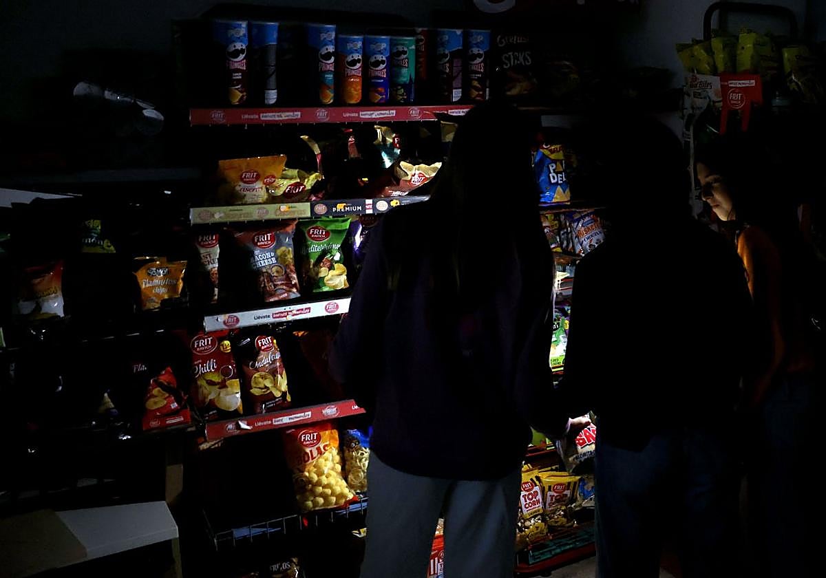 Varios clientes iluminan con el móvil en un supermercado de Barcelona el día del apagón.