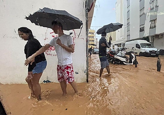Varias personas sortean las inundaciones de Ibiza.