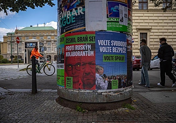 Personas pasan junto a carteles electorales en una calle de Praga.