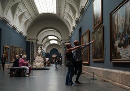 Una pareja señala el cuadro de 'El Lavatorio' de Tintoretto en el Museo del Prado.