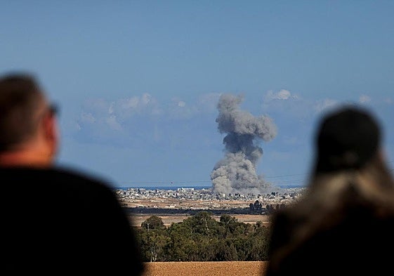 Dos personas observan una explosión en la Franja de Gaza.