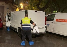 Dos empleados del retén fúnebre introducen en el furgón dos bolsas con los huesos humanos en la calle Luis Fenollet.