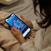 Una niña maneja su móvil en la cama.