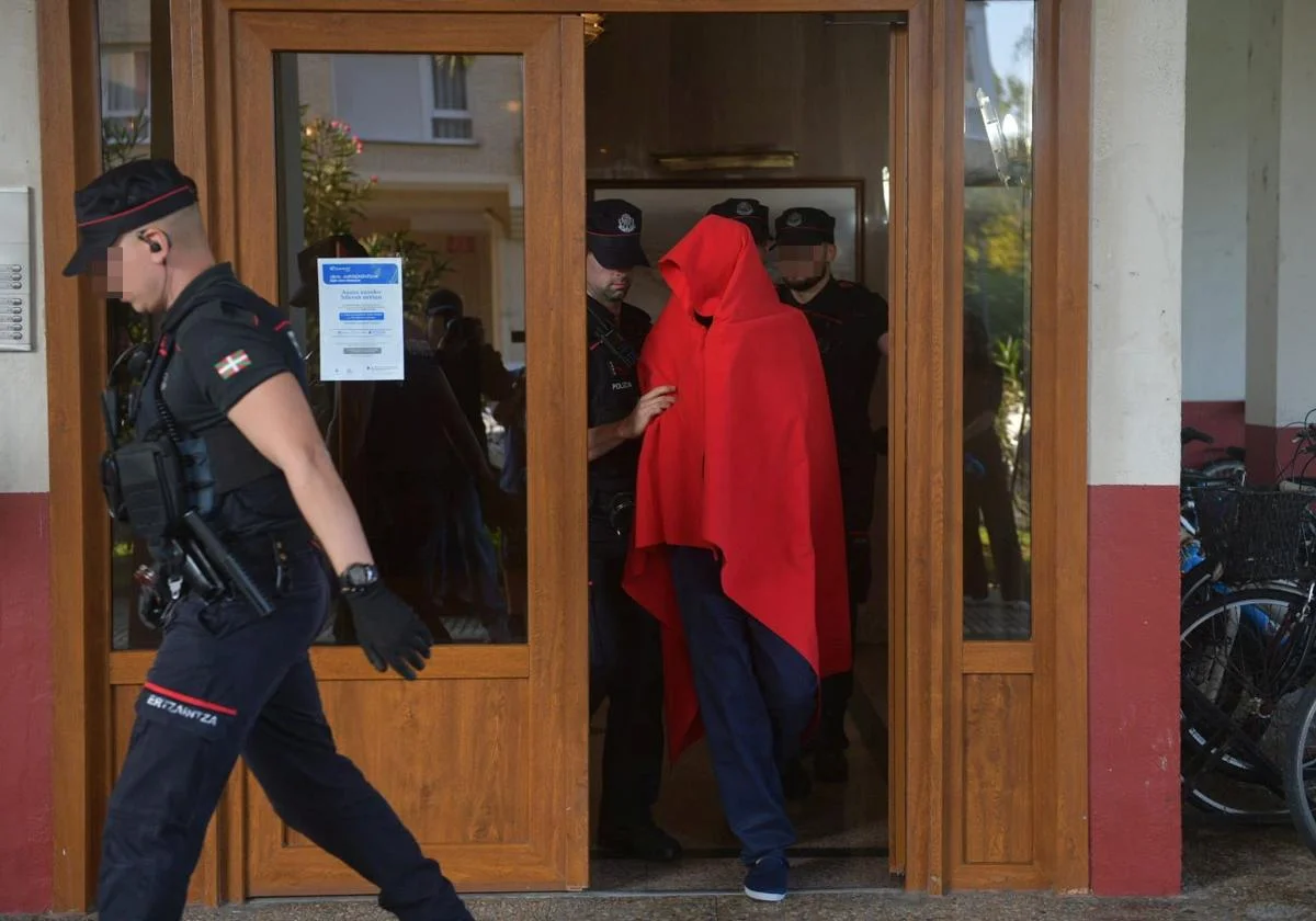 El detenido ha salido de la vivienda acompañado de varios agentes de la Ertzaintza y cubriendo su rostro con una manta roja.