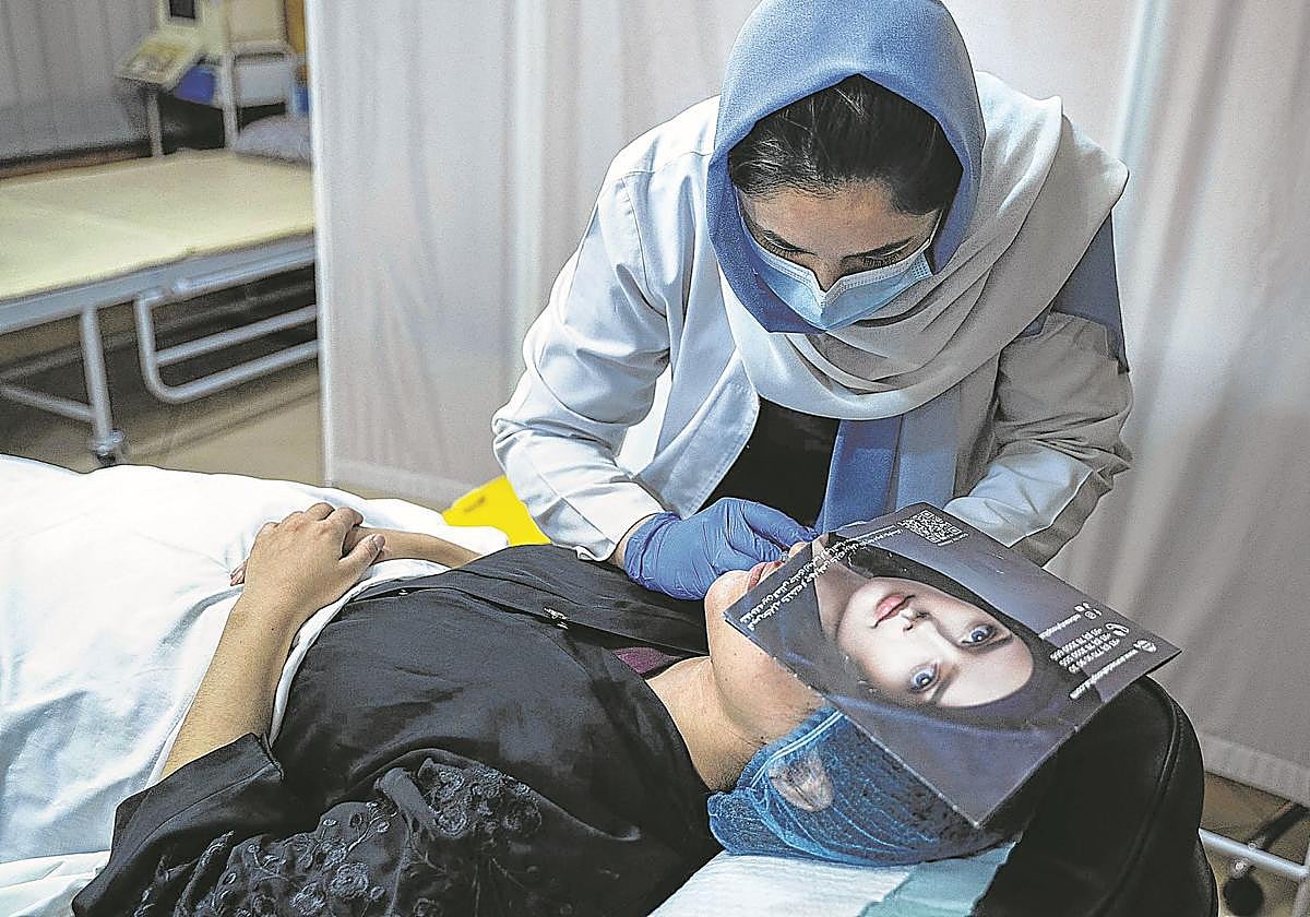 Una doctora copia de un panfleto el modelo de labios elegido por una paciente.