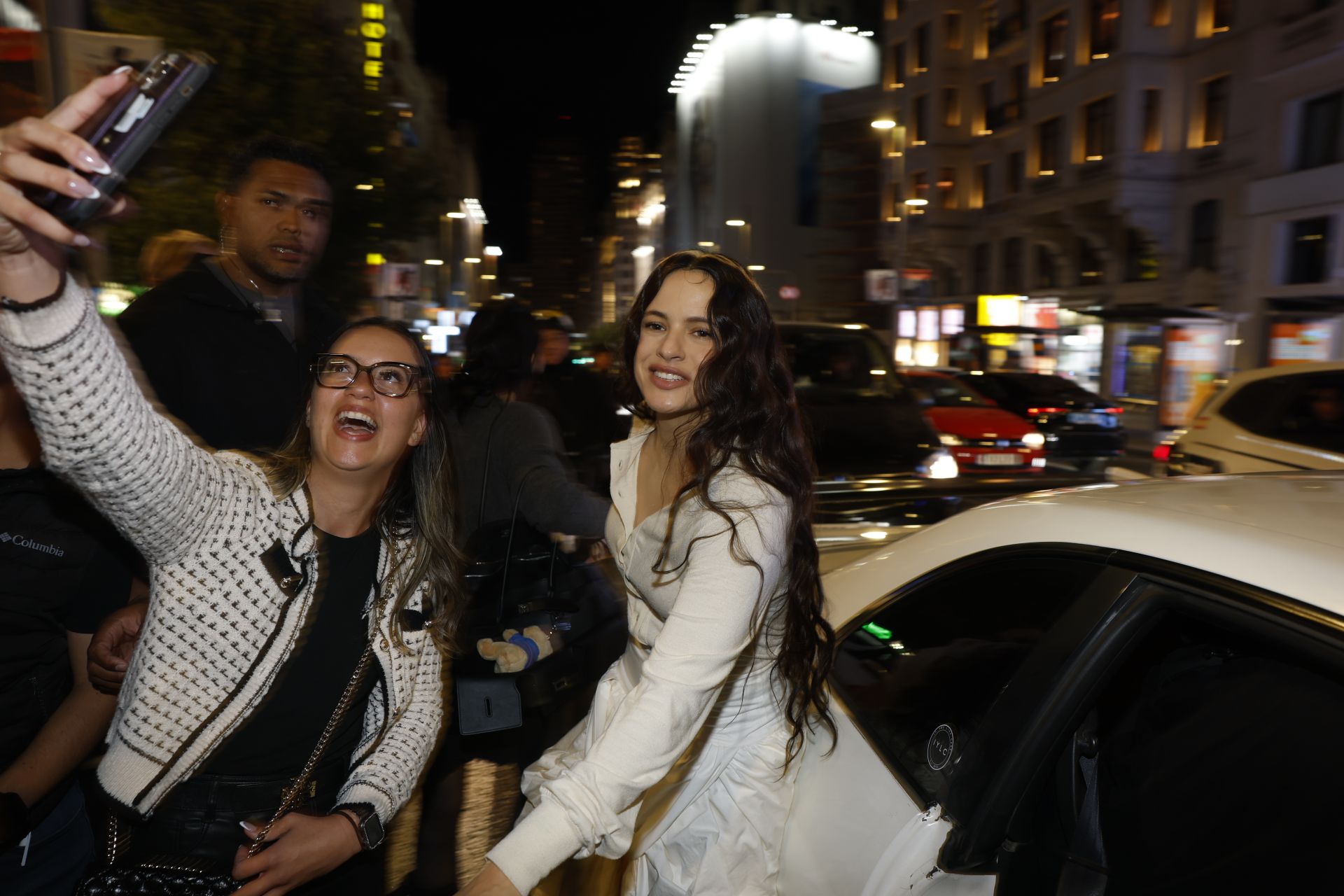 Imagen secundaria 1 - En las dos primeras imágenes, Rosalía llegando a la plaza de Callao y haciéndose un selfi con varias fans; en la última, cartel promocional de 'Lux', su nuevo disco.