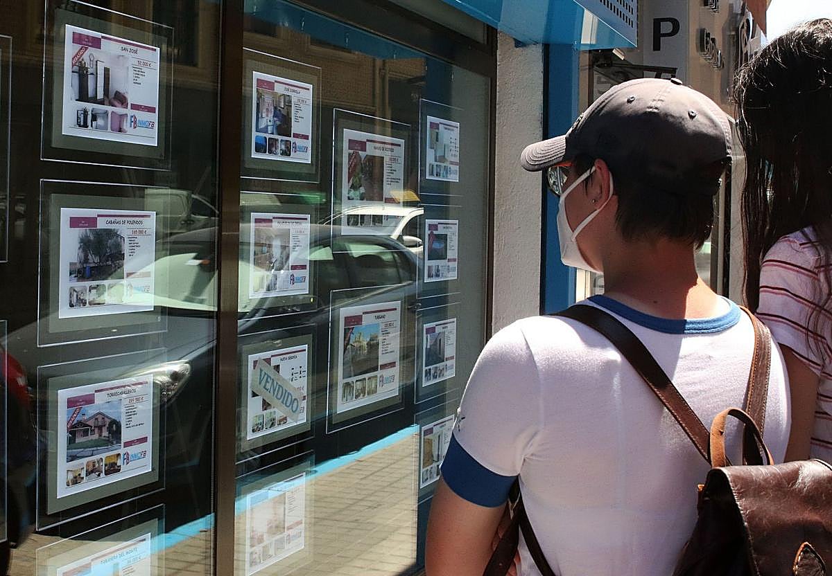 Dos personas miran anuncios de vivienda en una inmobiliaria durante la crisis sanitaria