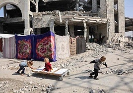 Tres niños juegan en las ruinas de Gaza City.