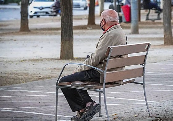 Una persona mayor sentada en un banco.